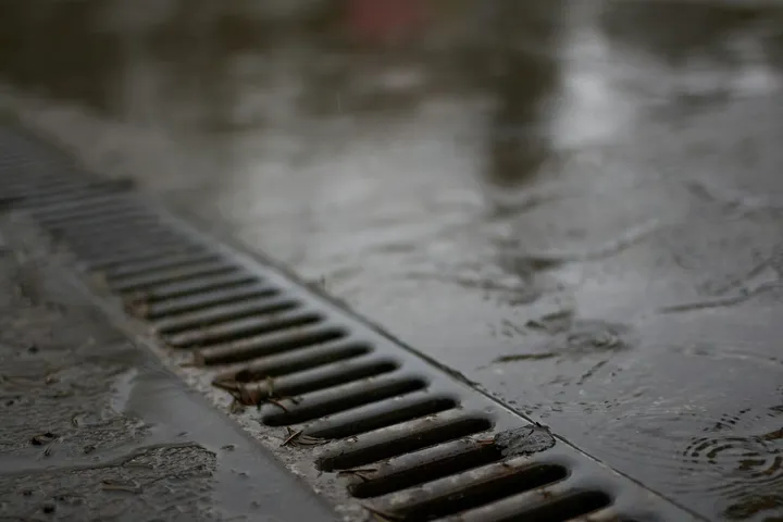 Rain falling on a metal drainage channel grate