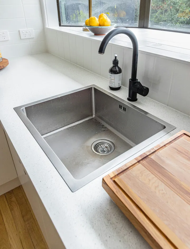 Stainless steel undermount kitchen sink with a black tap and open waste