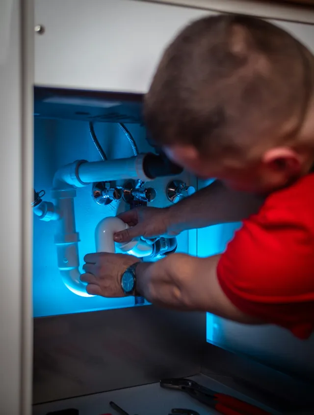 Plumber working on pipework under a kitchen sink